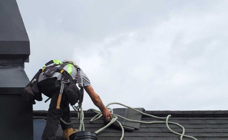 Uneven shingles and loose flashing visible on a residential roof after heavy weather.